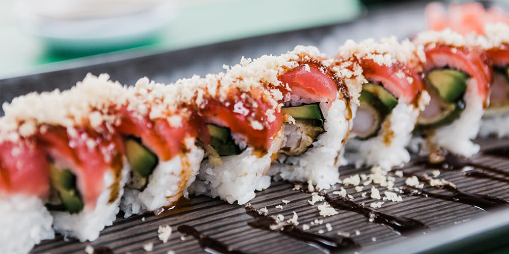 A row of sushi rolls served with pickled ginger