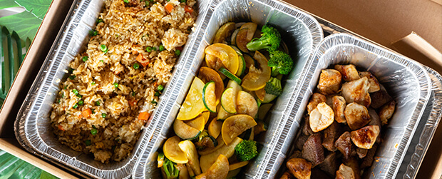 Catering trays of fried rice, vegetables and grilled meat