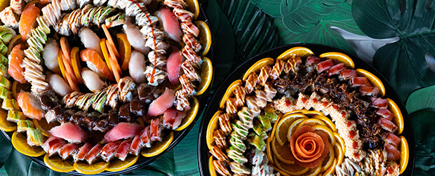 Sushi rolls and sliced fish arranged on catering platters