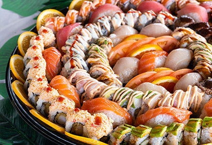 A catering platter filled with sushi rolls and sliced fish