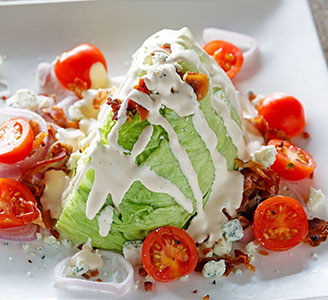 A wedge salad topped with dressing and cherry tomatoes